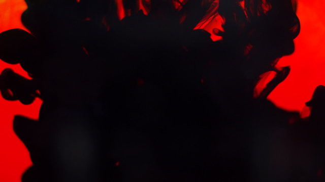 Abstract dynamic flow of black ink in water on red background