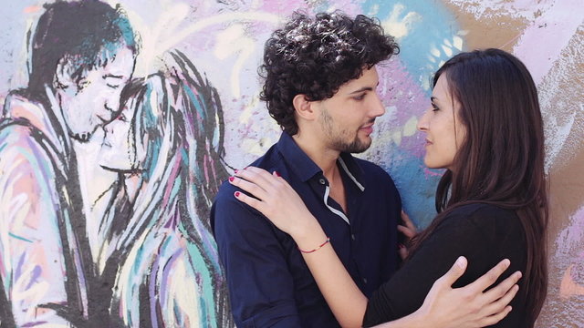 loving couple kissing in graffiti behind a couple kissing - love - hug