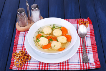 Soup with meatballs and noodles in bowl on wooden background