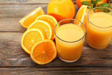 Naklejka na ściany i meble Glass of orange juice and slices on wooden table background