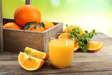 Glass of orange juice with crate of oranges and slices