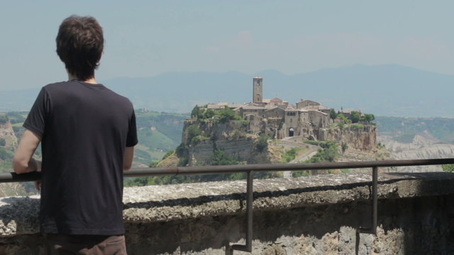 man looks at a medieval village ( civita di bagnoreggio) " the city that dies "