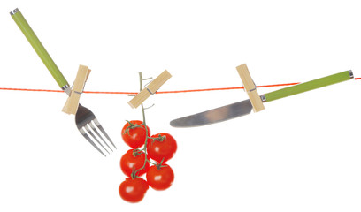 Fork, knife and ripe red tomatoes hanging from clothesline