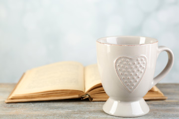 Cup of tea and book on table, on light background