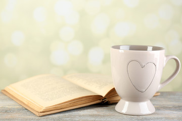 Cup of tea and book on table, on light background