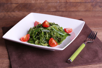Seaweed salad with slices of cherry tomato in plate