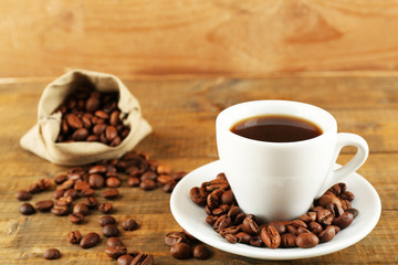 Cup of coffee with beans on rustic wooden background