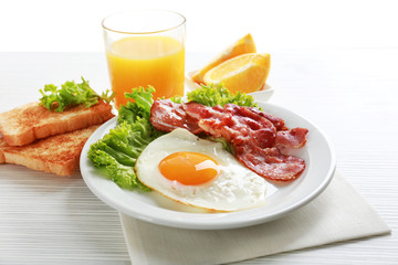 Bacon and eggs on color wooden table background