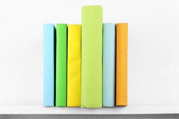 Colorful covered books on bookshelf and white wall background