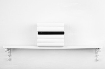 Blank books with black one on bookshelf on white wall
