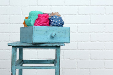 Different scarves in color drawer on white brick wall