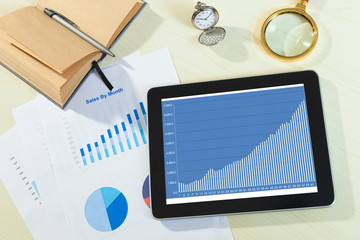 digital tablet and smartphone with financial chart report, paper