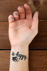Female arm with tattoo on wooden background