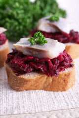 Rye toasts with herring and beets on tablecloth background