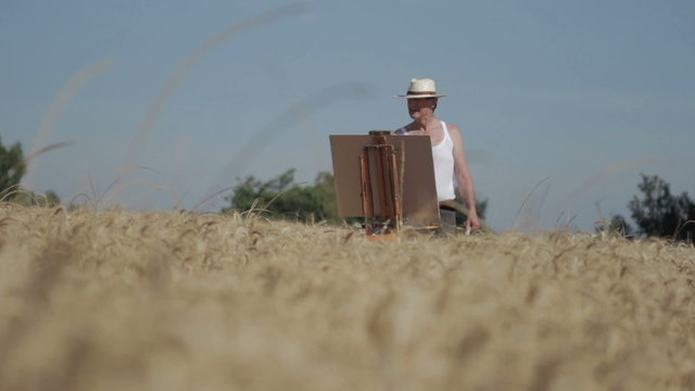 painter in the middle of a wheat field paints a beautiful landscape, brush