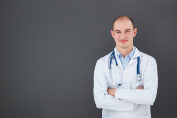 Portrait of confident doctor on gray background looking at the c