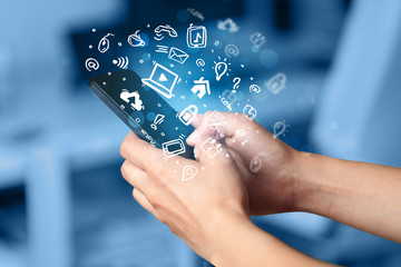 Hand holding smartphone with media icons and symbol