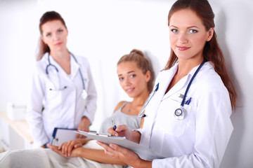 Smiling female doctor with a folder in uniform standing at