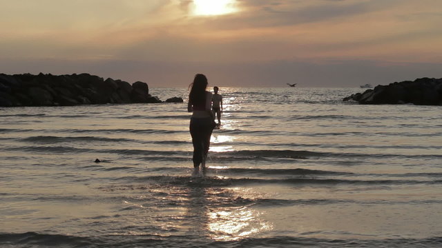 girl in love runs to her boyfriend into the sea - hugs and kisses - sunset