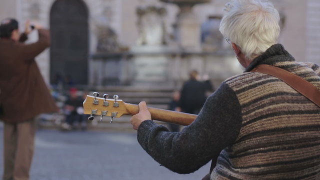 Street artist playing guitar in a typical square in rome