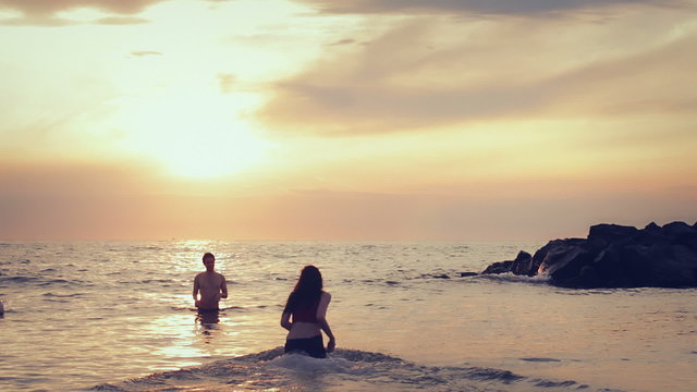 dressed woman in love runs to her man into the sea - hugs and kisses - sunset