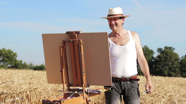 painter with an easel in the middle of a wheat field