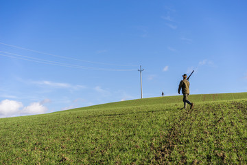 Gamekeeper walks over field.