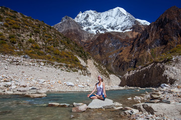 Fototapeta premium Young woman is practicing yoga at mountain lake