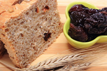 Baked wholemeal bread, dried plums and ears of wheat