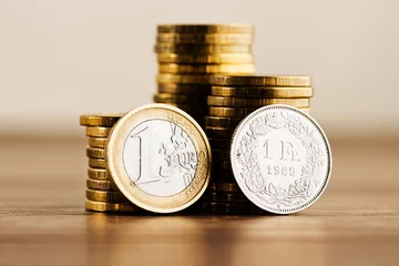 Foto op Canvas een euromunt en een Zwitserse frank © Valeri Luzina