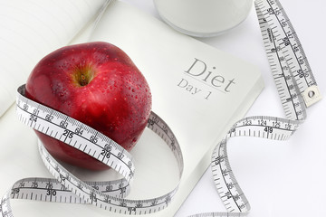 Red apple on a notebook and measuring tape, Diet concept.