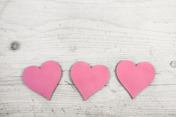 Drei rosarote Herzen zum Valentinstag auf Holz Hintergrund