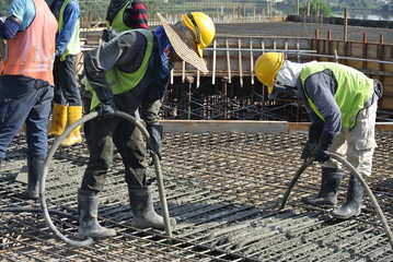 Construction Workers Using Concrete Vibrator