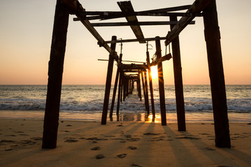 Decaying wooden bridge in the sea with sunset