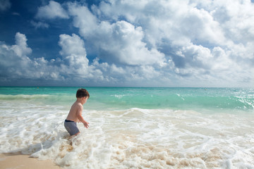Fototapeta na wymiar Boy enyojs summer day at the tropical beach.