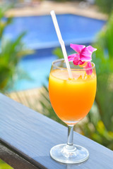Orange juice with orchid and swimming pool view