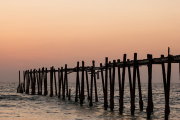Decaying wooden bridge in the sea with sunset