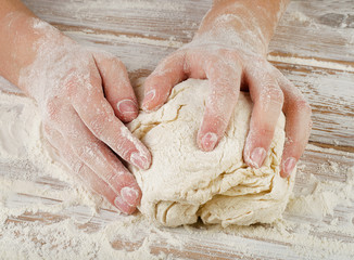 Woman  preparing dough  on a wooden table.