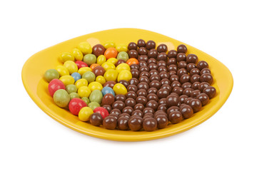 Chocolate balls and multicolored peanut glaze on a yellow plate