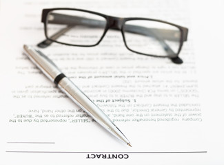 silver pen and eyeglasses on sales contract