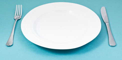 empty plate with fork and knife on green