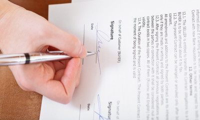 buyer signs a contract by silver pen