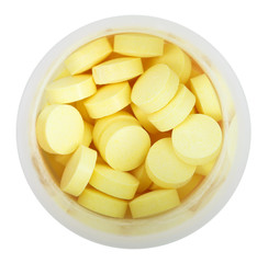 yellow pills in round plastic bottle close up