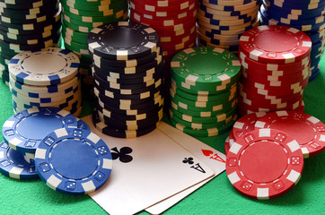 Red, blue, green, white and black poker chips pile and aces