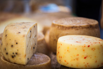 Wheels of cheese seasoned with herbs to sell on stall