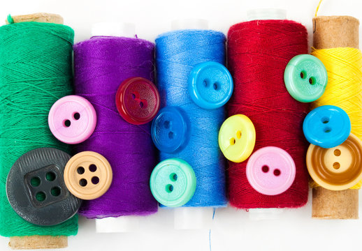 color buttons and thread bobbins on the white background