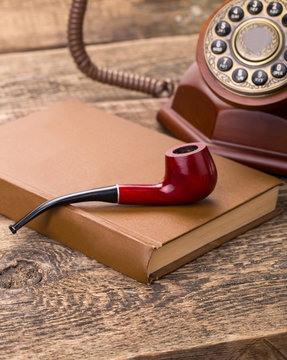 tobacco pipe old telephone and book on wooden palette