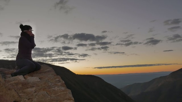 Woman on promontory at sunset