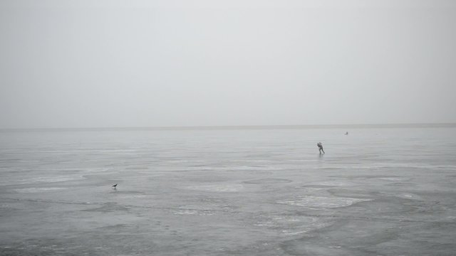 Winter fisherman making hole in ice with an ice chisel