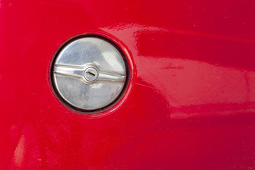metal fuel tank cap of old red car with the keyhole inside